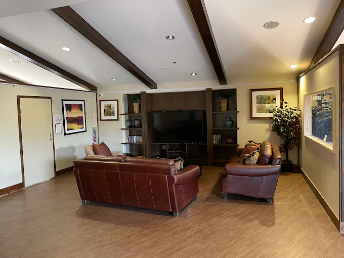 Lounge area with leather couches, TV, and wall decor.