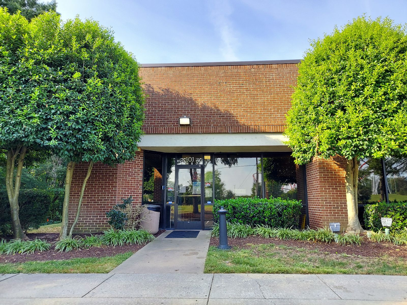 Brick rehab facility with glass doors and trimmed trees in front