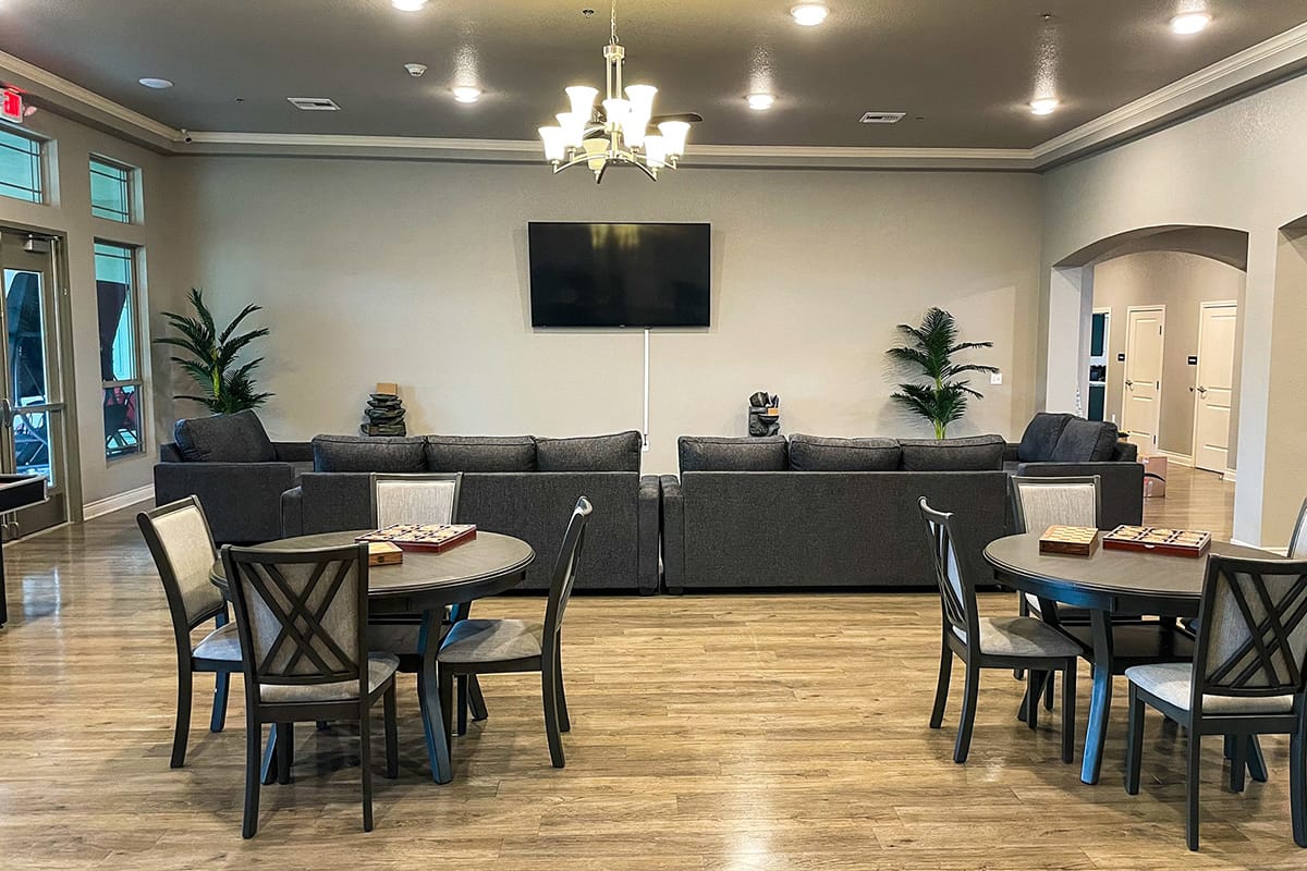 Lounge with sofas and circular tables in front of a TV.
