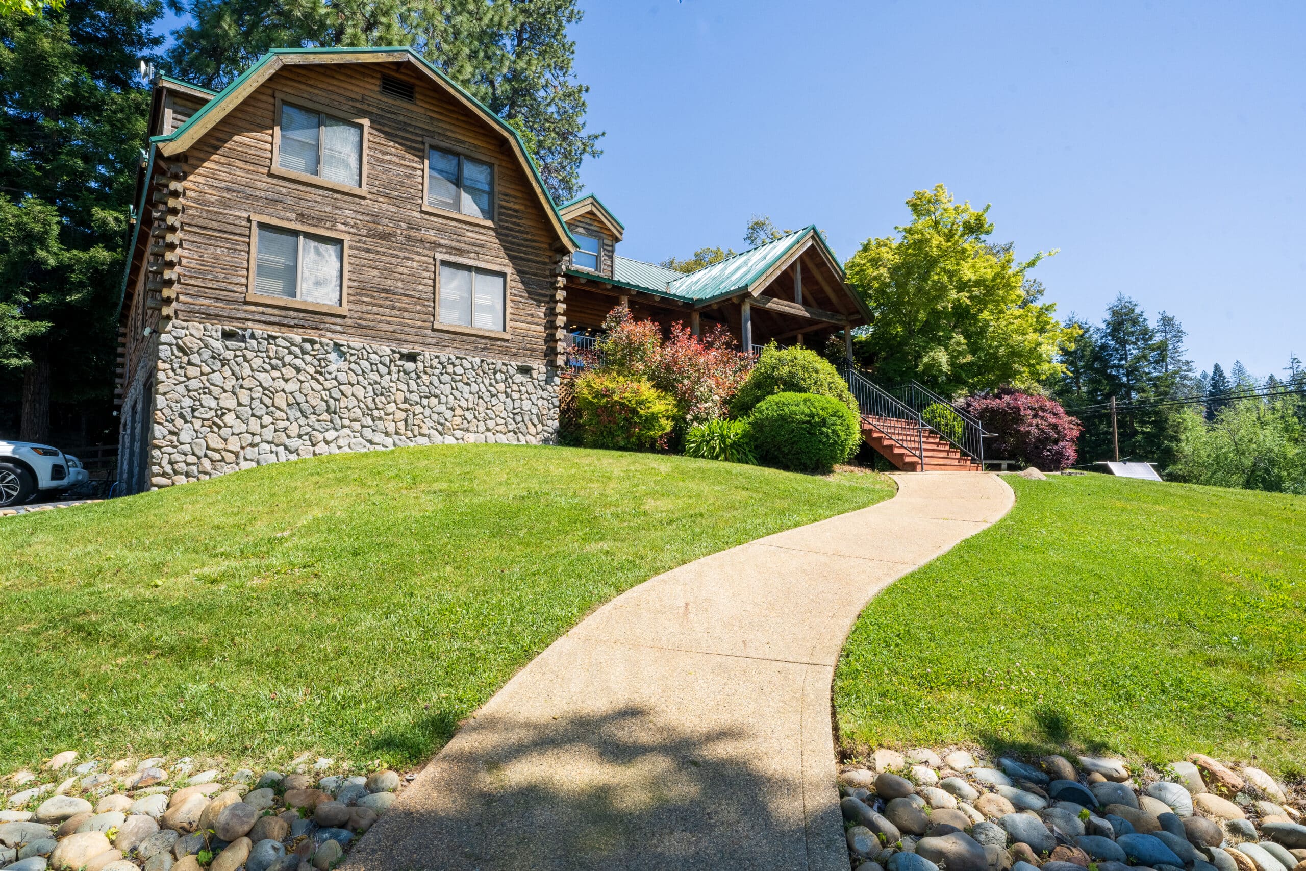 og-style residential treatment center with stone foundation, manicured lawn, and staircase leading to the main entrance