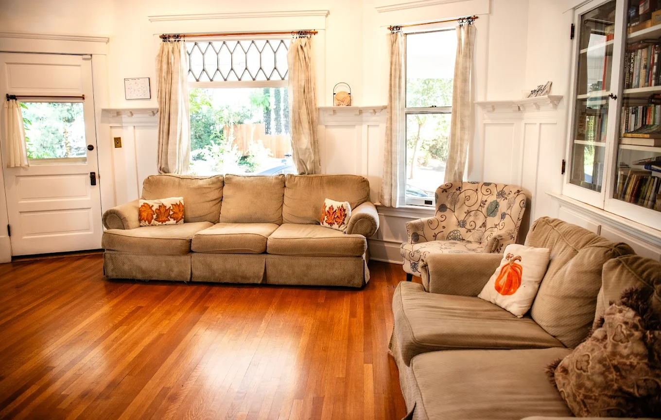 Cozy living room with beige sofas, patterned armchair, and bookshelves at Liberty House Recovery
