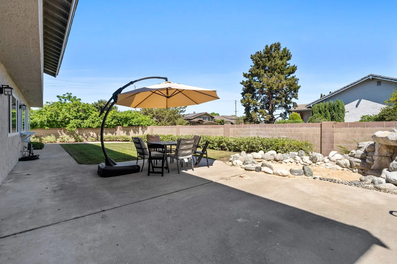 Patio table with umbrella and chairs beside garden wall