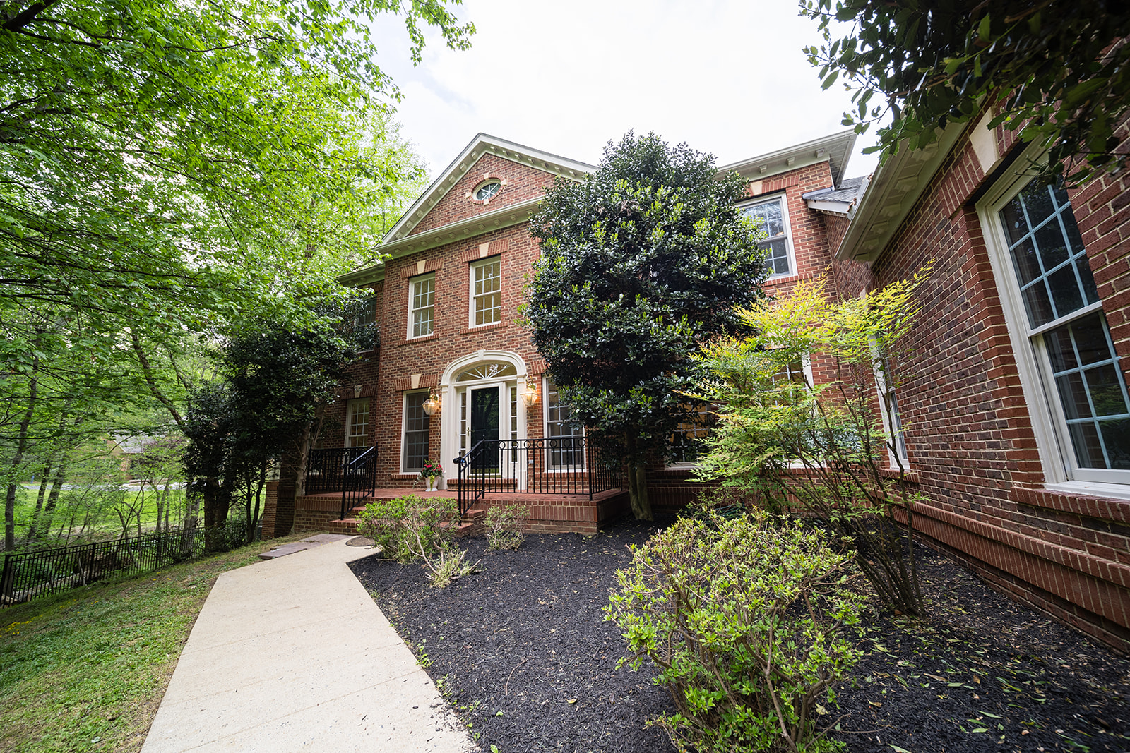 Brick front entrance with landscaped path and trees