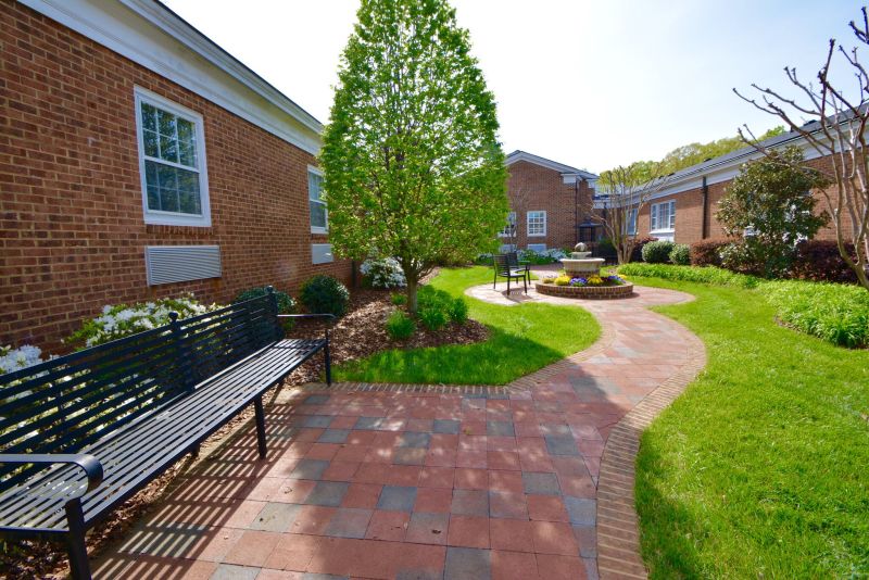 Brick courtyard with benches and a tree-lined walkway