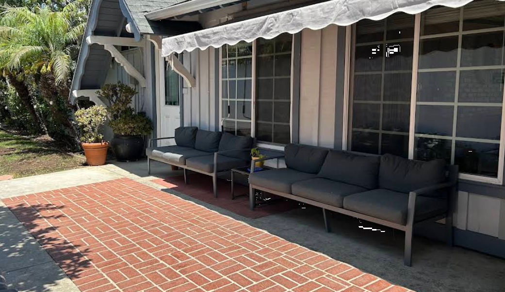 Brick patio with gray outdoor sofas and shade awning