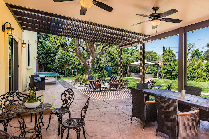 A covered outdoor patio with seating and ceiling fans.