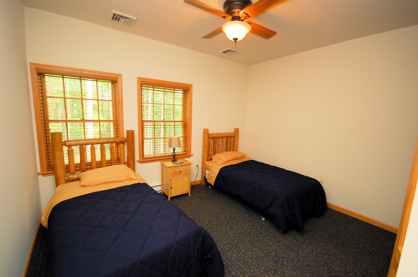 A shared bedroom with two wooden twin beds and natural light