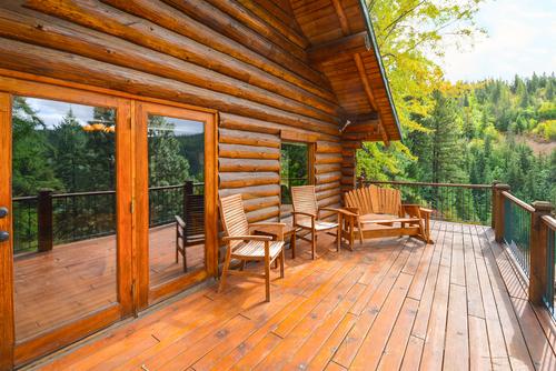 Outdoor wooden deck with seating overlooking a forest view.