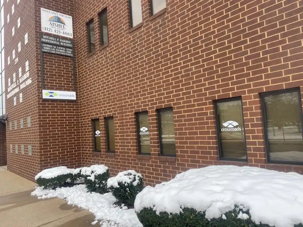 Brick clinic building with Crossroads signage and snowy shrubs