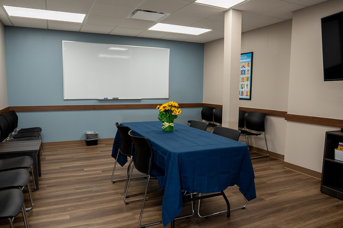 Group room with table, chairs, whiteboard, and television