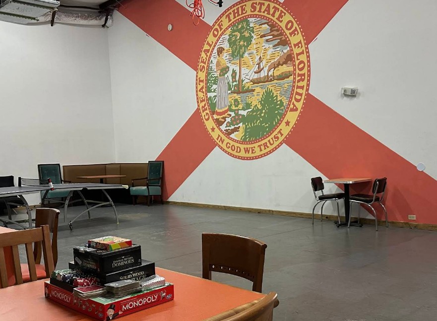 Activity room with games, tables, and Florida mural