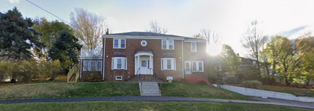 Two-story red brick building with white trim and front steps