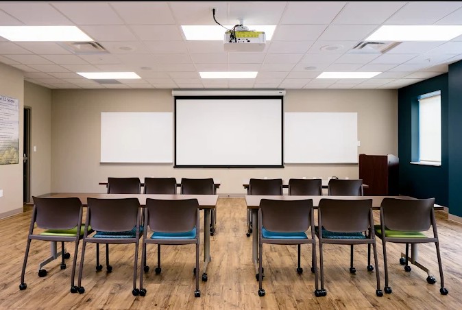 Classroom with chairs, projector screen, and whiteboards