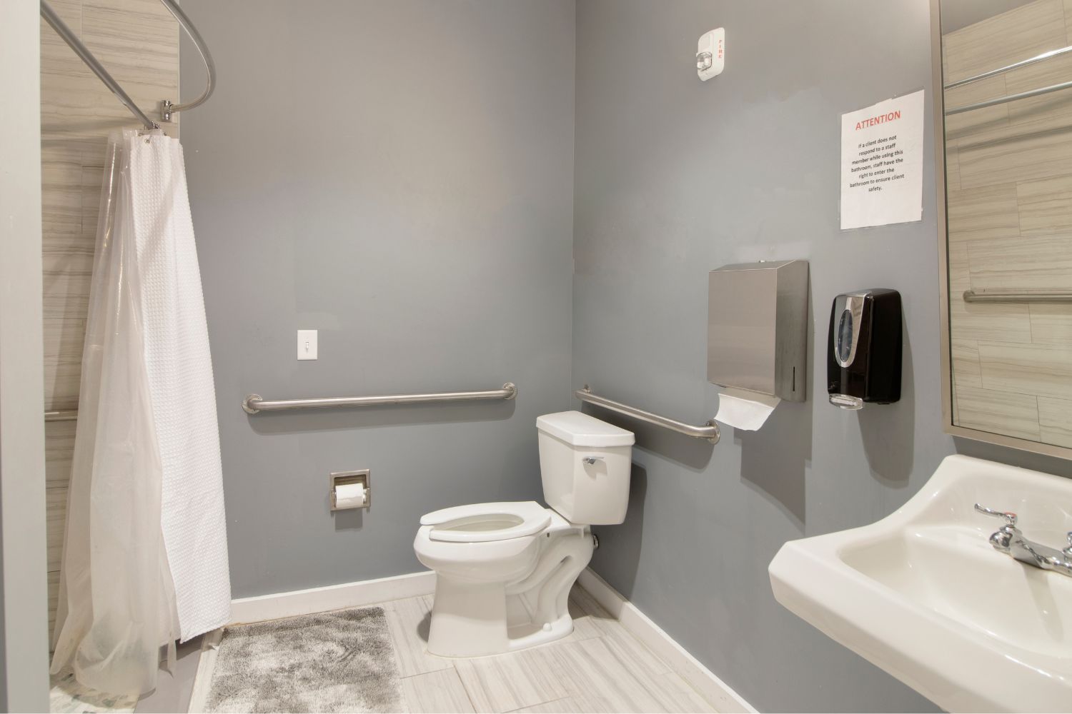 Clean bathroom with shower, toilet, and safety handrails