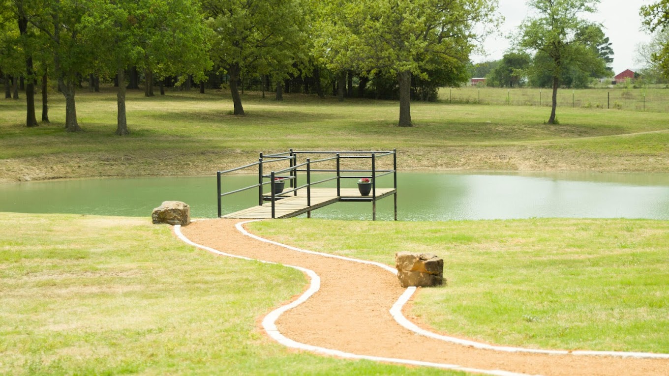 A peaceful pond with a wooden dock and surrounding greenery.