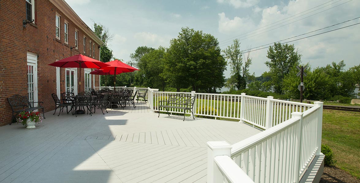 Outdoor porch with tables and seating overlooking greenery