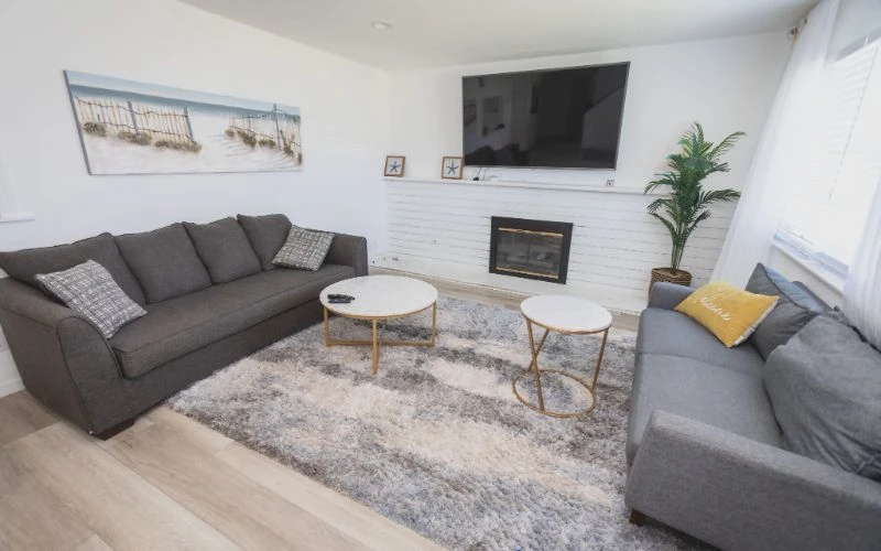 Cozy lounge with gray sofas, rug, and TV above fireplace