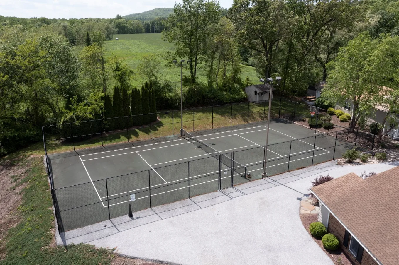 Outdoor tennis court surrounded by trees and hills