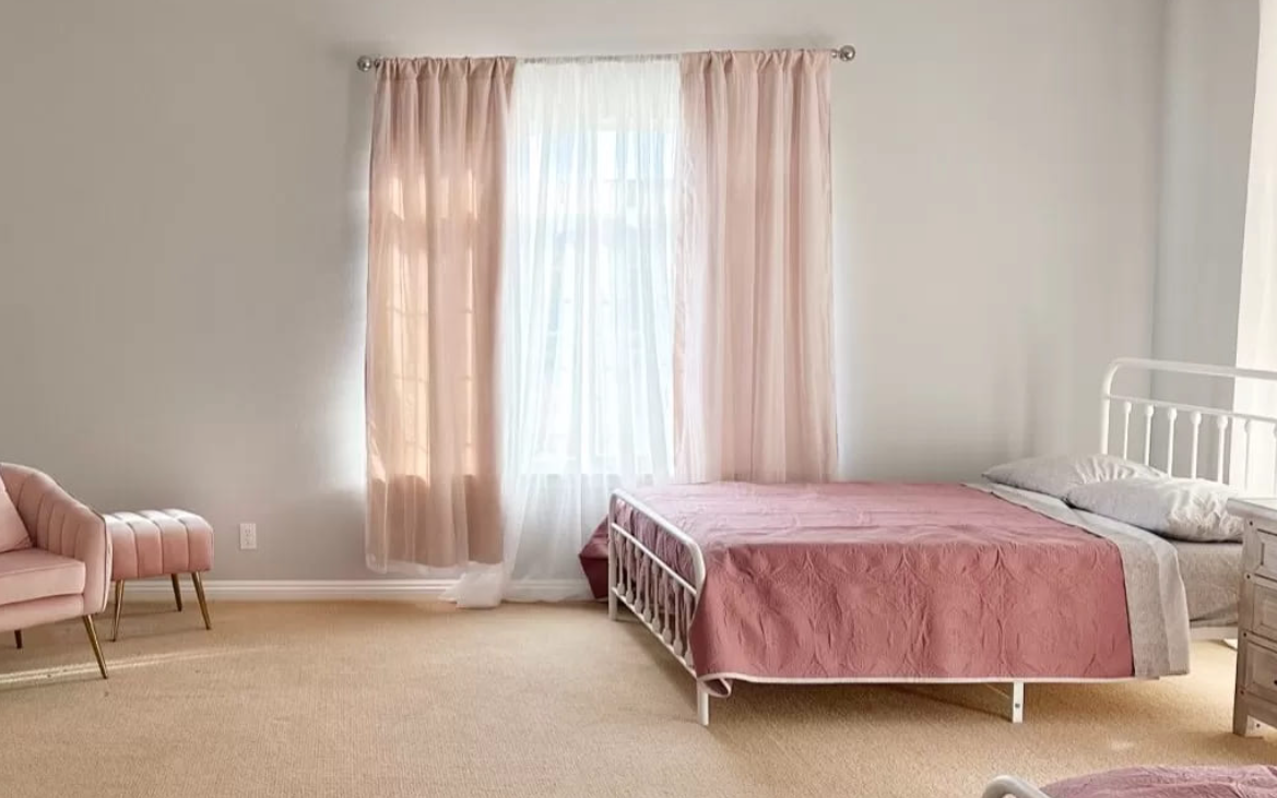 Soft pink bedroom with matching chair and bright natural light