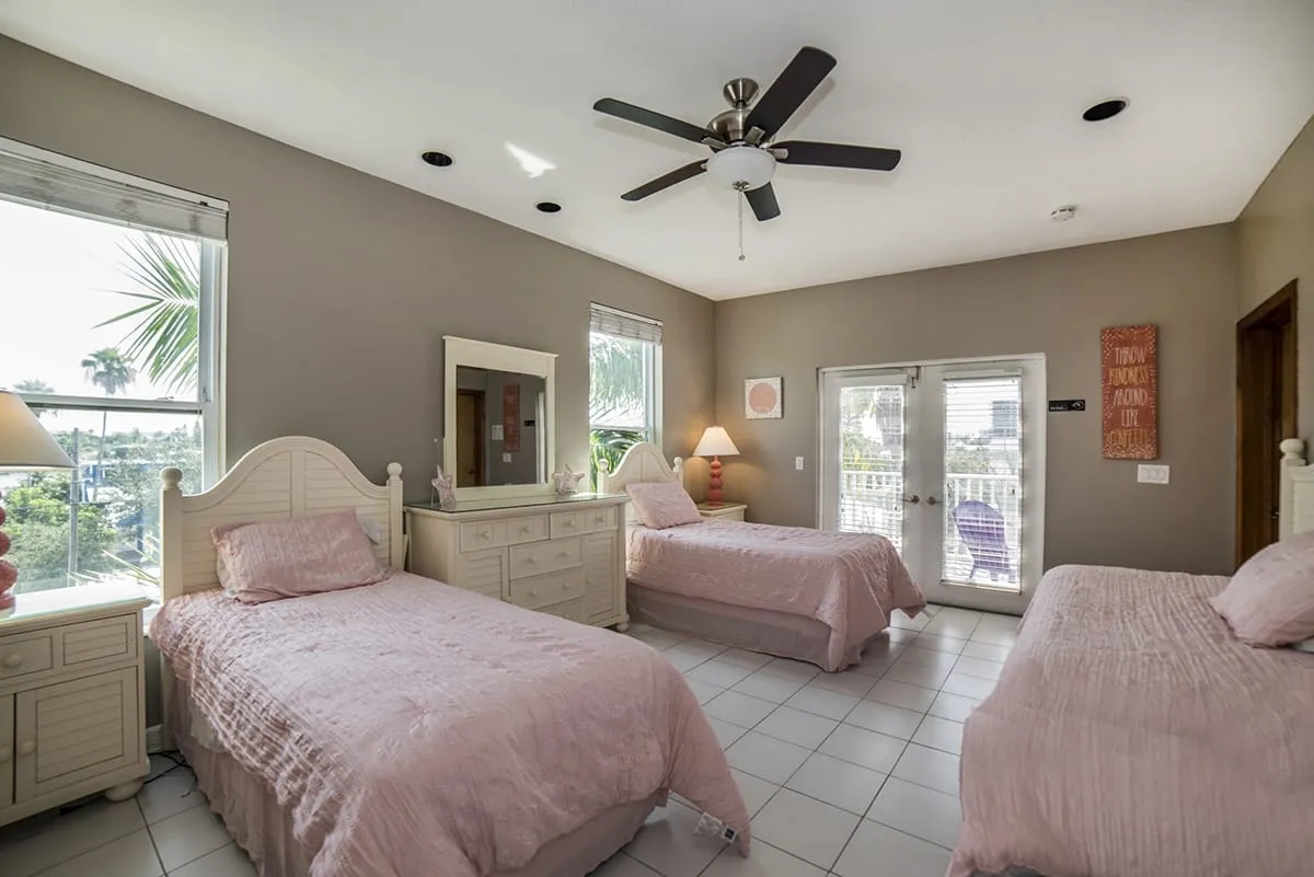 Bright room with three pink twin beds and patio access