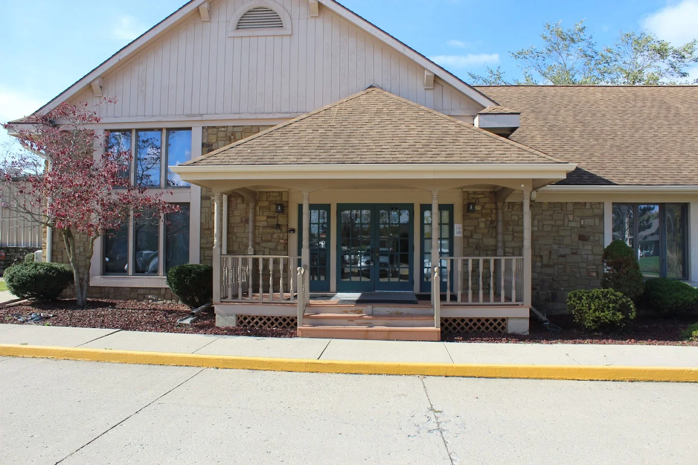 Front entrance of Bridges of Hope facility in Anderson featuring a covered porch, stone facade, and blue double doors