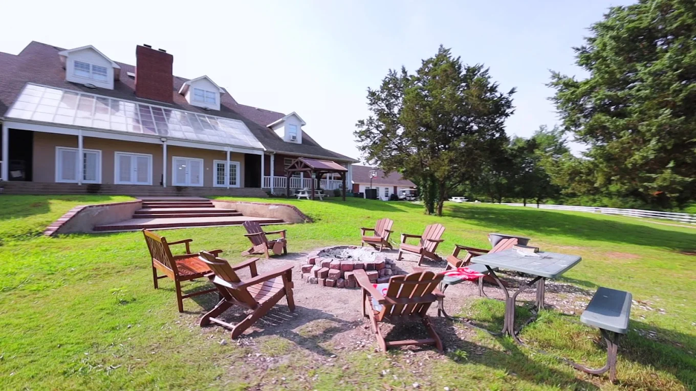 Outdoor fire pit surrounded by wooden Adirondack chairs on the landscaped grounds of Discovery Point Retreat
