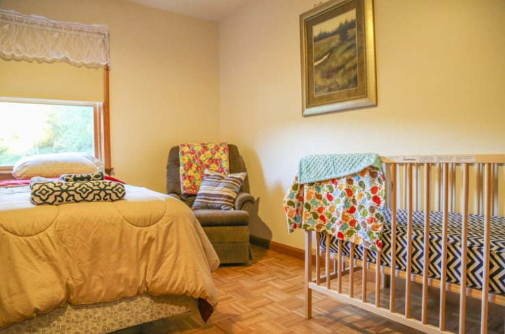 Warm bedroom with bed, recliner, and crib