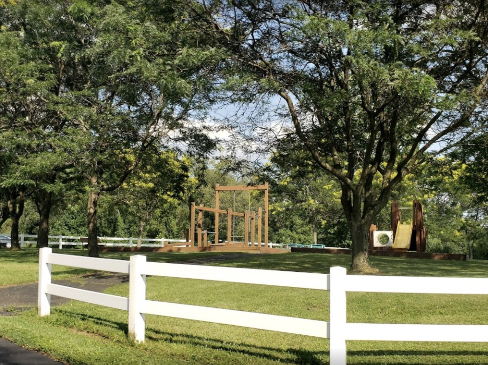 Playground and trees in fenced grassy area of recovery campus