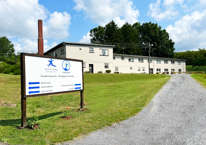 Outdoor sign showing directions and program logos