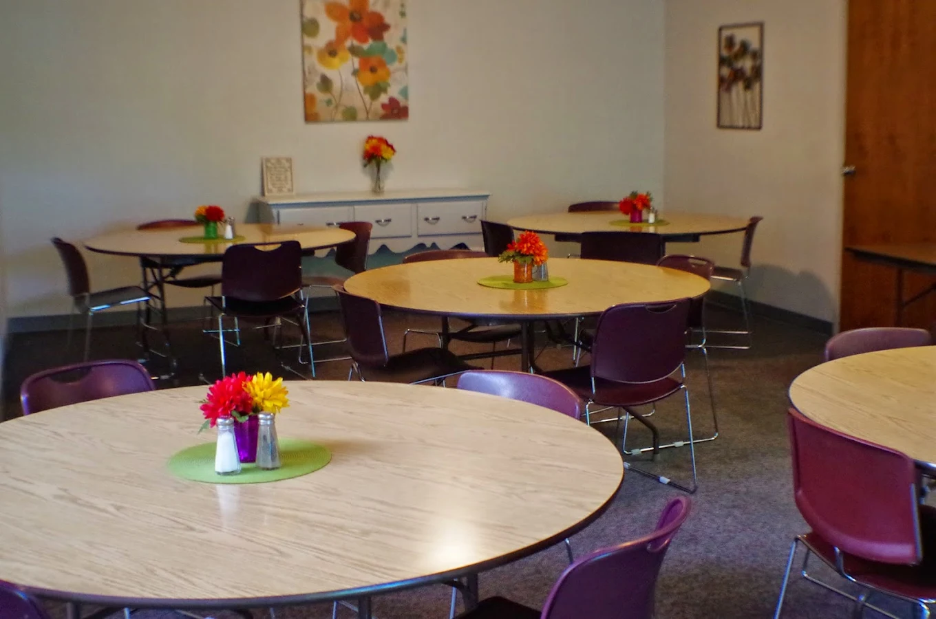 Rehab cafeteria with round tables and colorful flower centerpieces