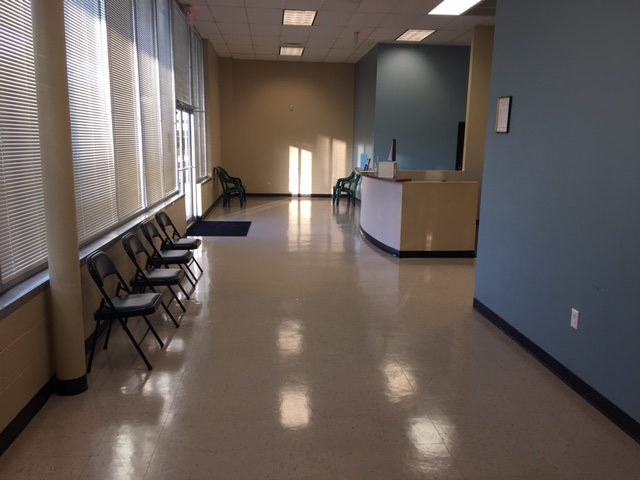 A waiting area with chairs along the window and a reception desk.