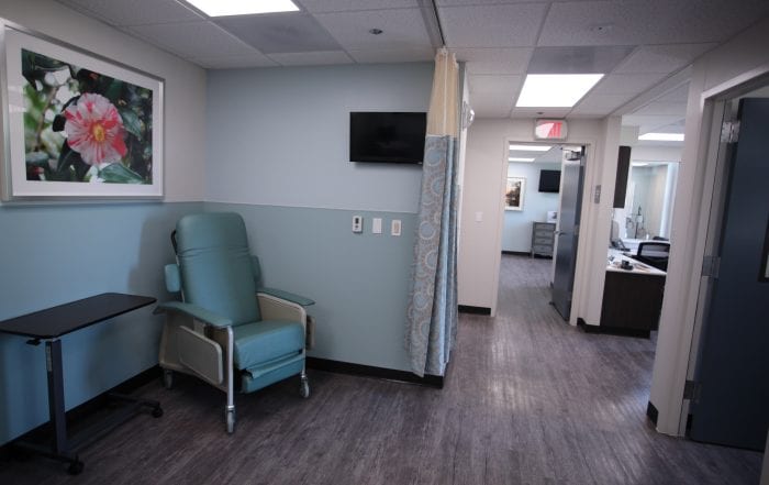 Medical recliner beside tray table and wall-mounted TV