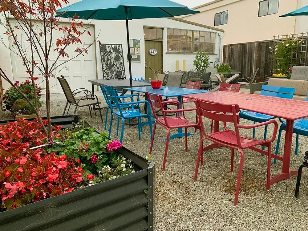 Outdoor courtyard with dining tables, umbrellas, and garden beds