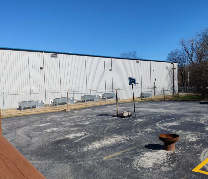 Outdoor basketball court with hoop and fenced yard