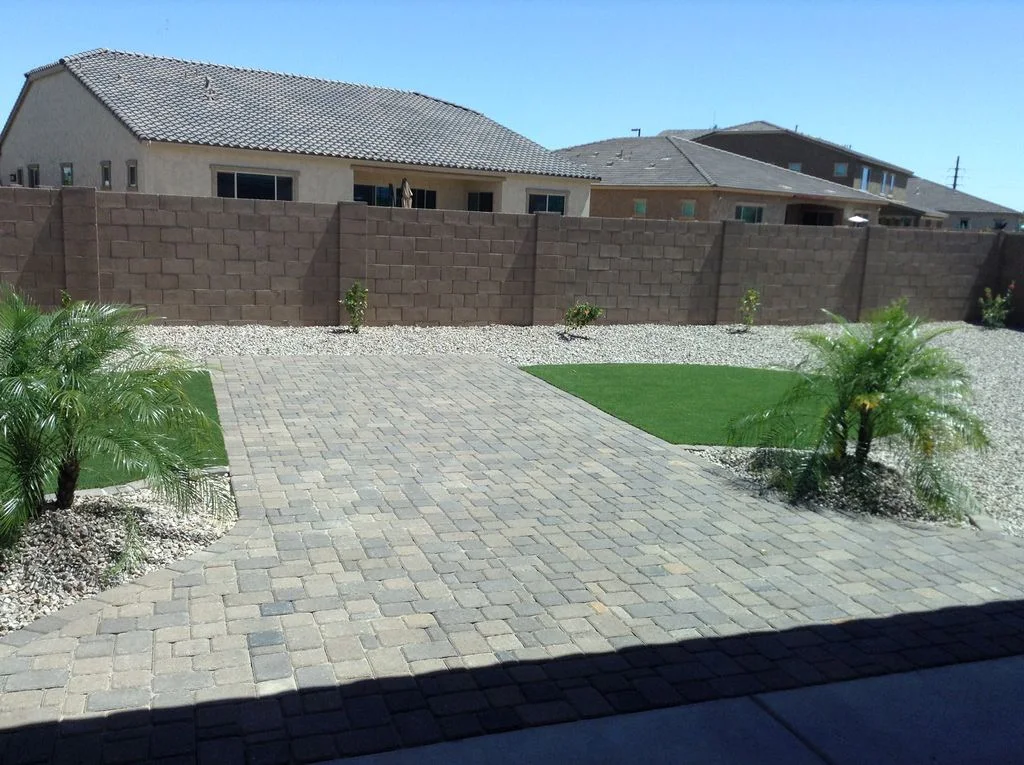Paved backyard with palm trees and green turf
