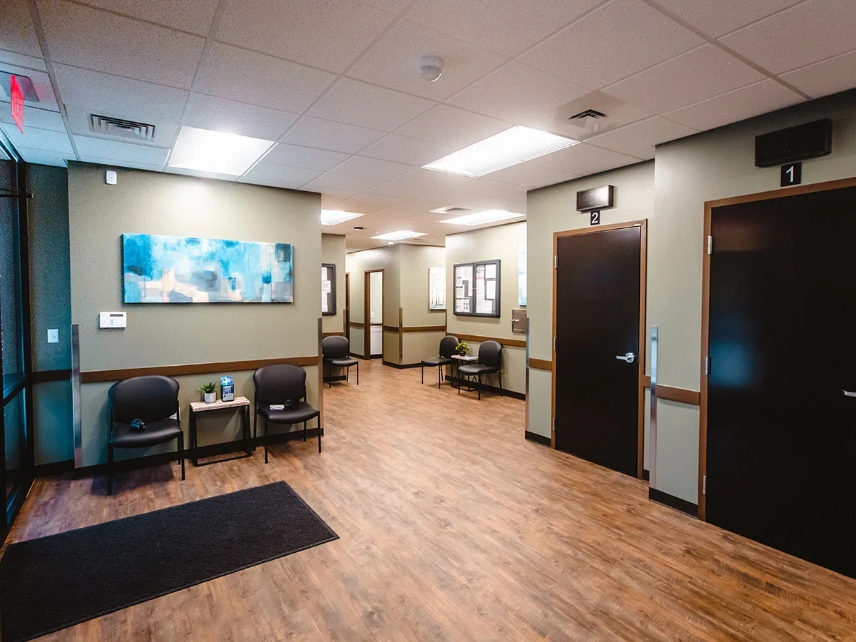 Clinic hallway with doors, chairs, and wall decor