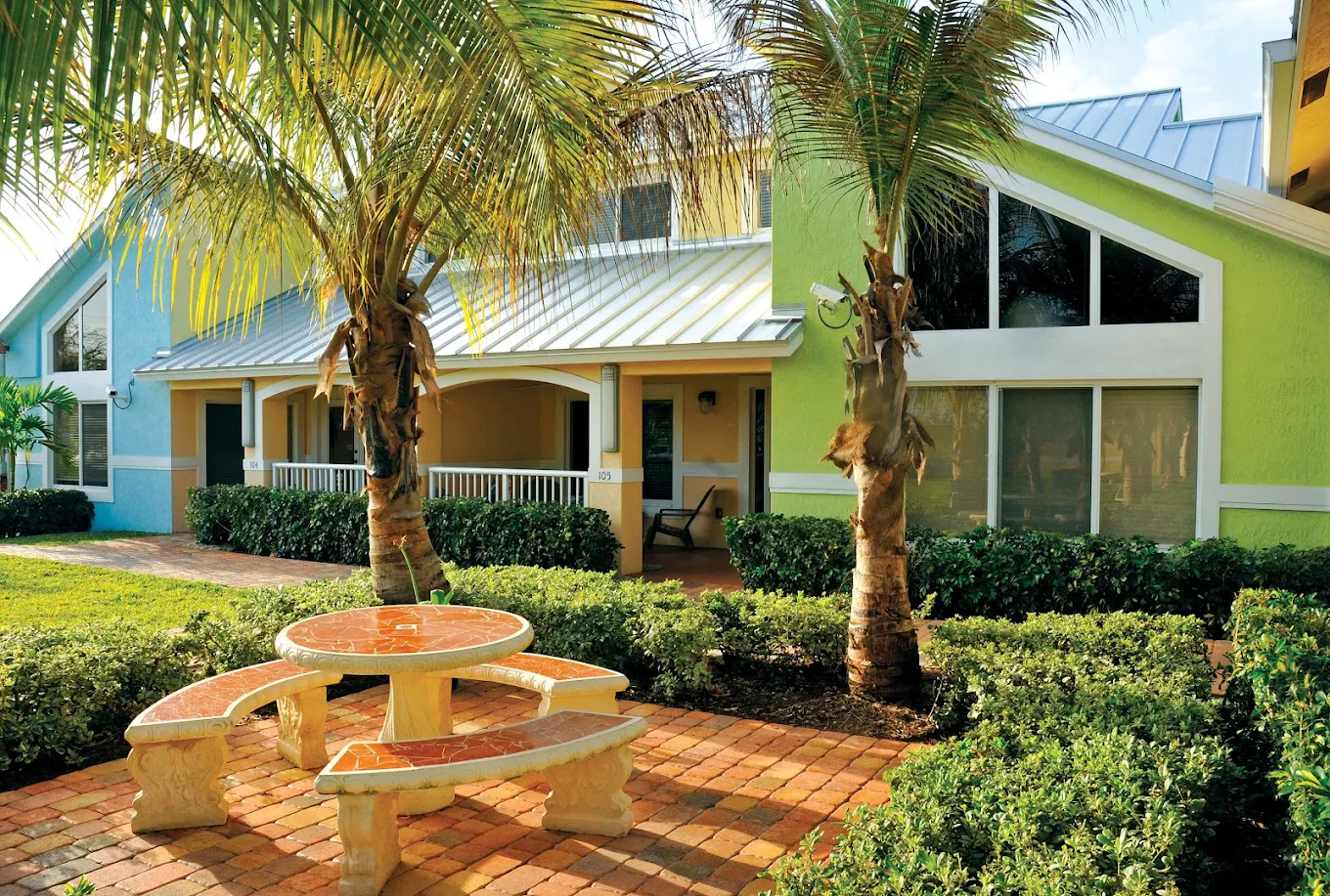 Stone picnic table under palm trees by residential building