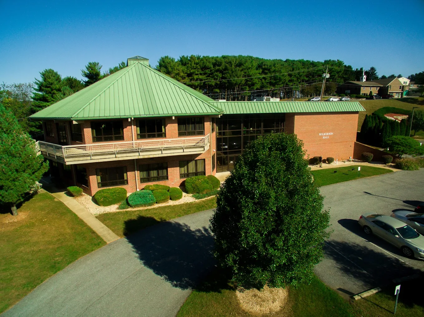 Brick building with green roof and tree-lined parking lot