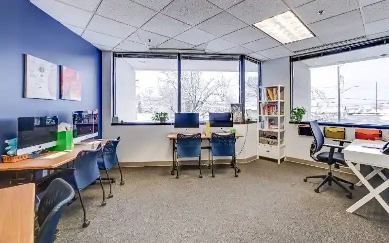 Bright study room with desks, computers, and large windows