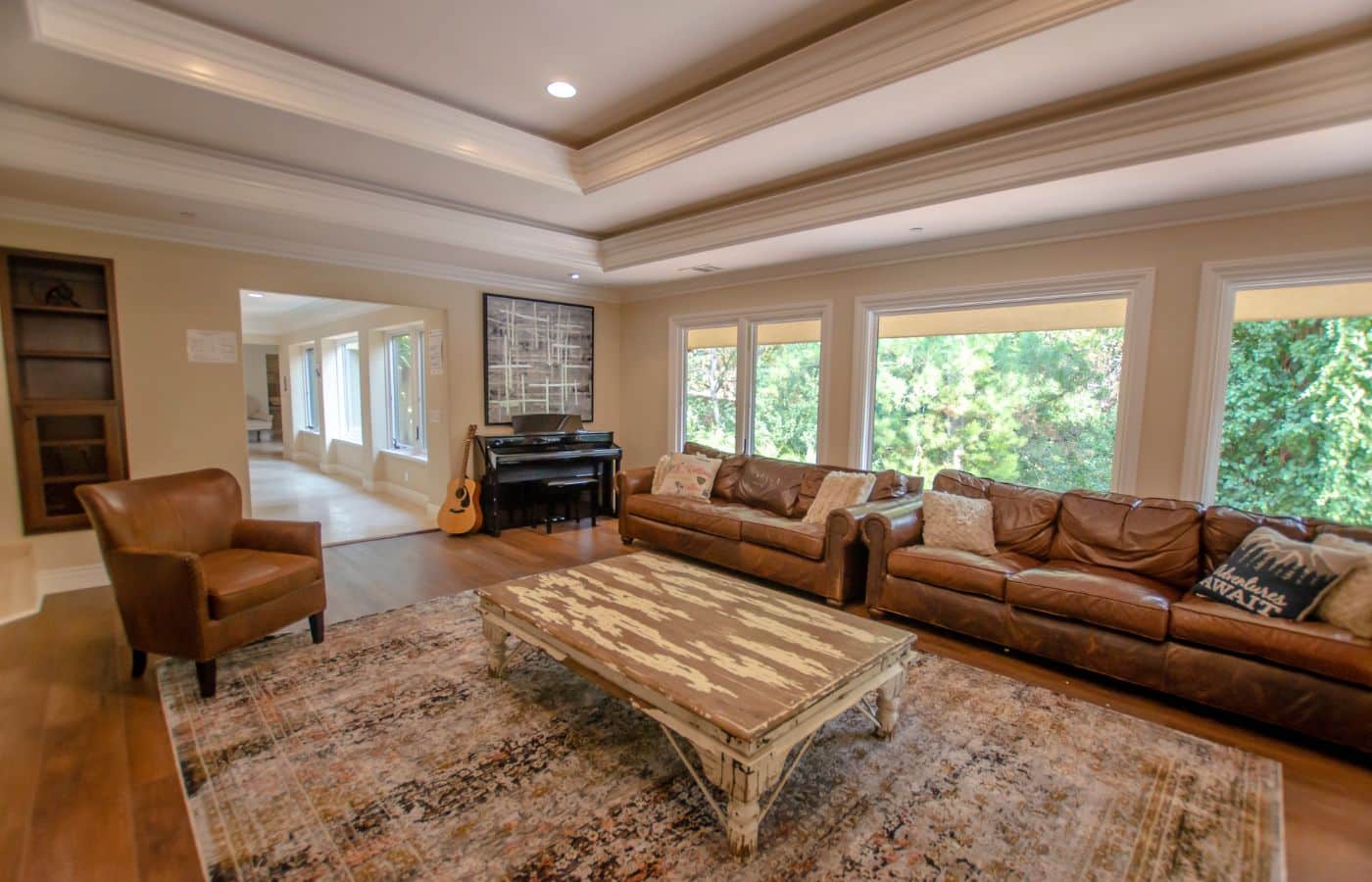 Bright lounge with leather sofas, piano, and large windows.