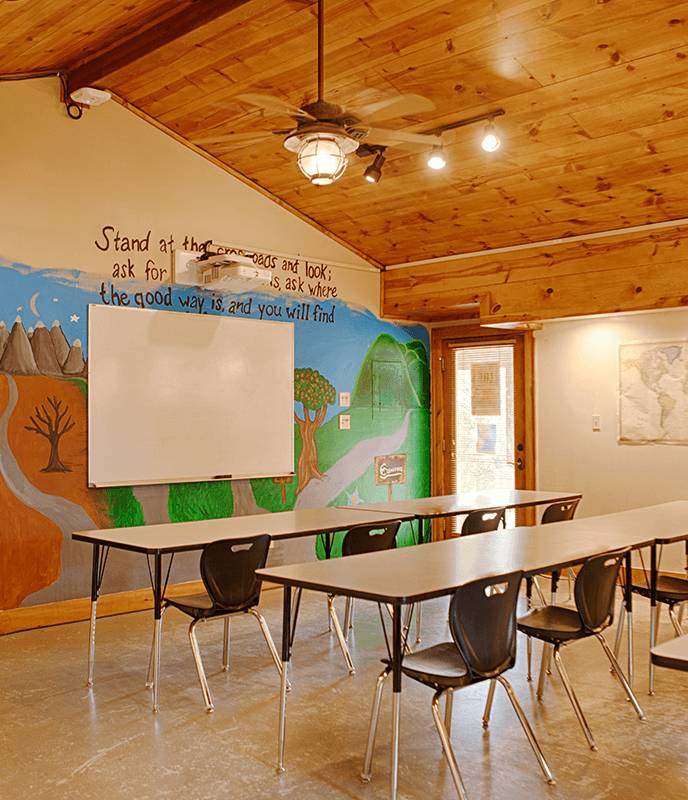 A warm classroom with wooden walls and a mural.