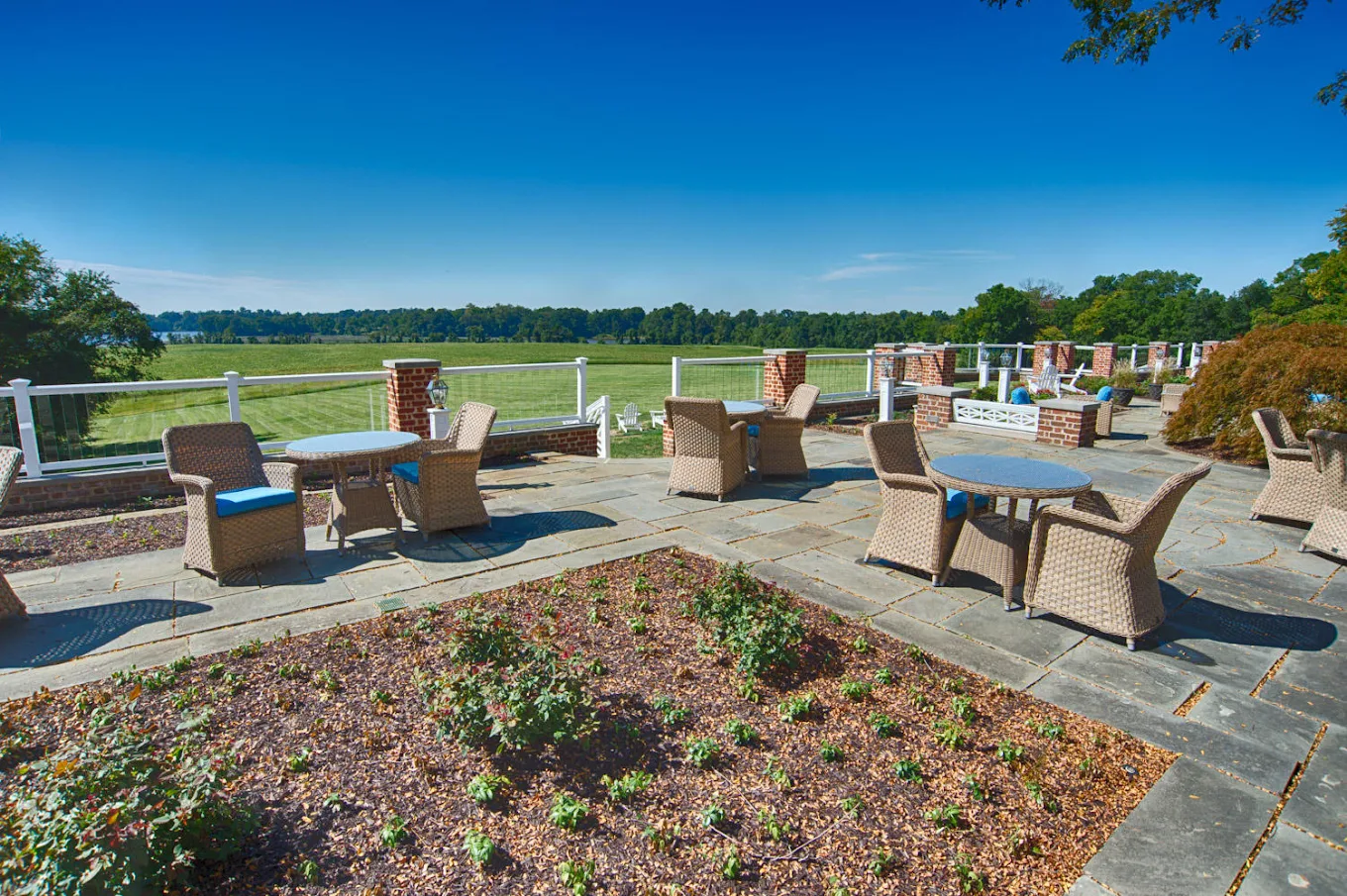 Outdoor patio with tables and chairs overlooking green grounds