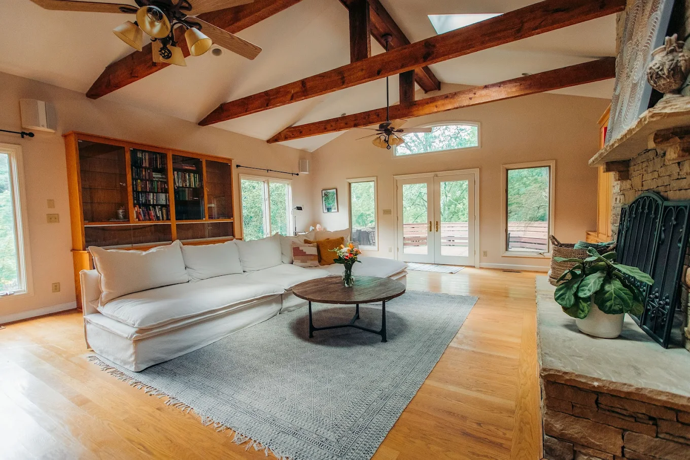 Comfortable lounge with large sectional sofa, wooden beams, bookshelves, and natural light
