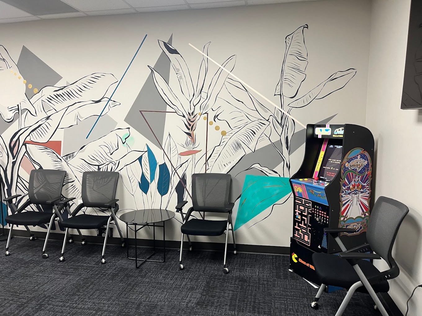 A lounge with modern art, chairs, and an arcade game.