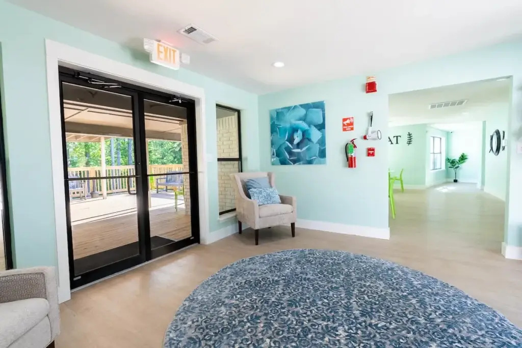 Bright hallway lounge with chairs and glass doors to patio.