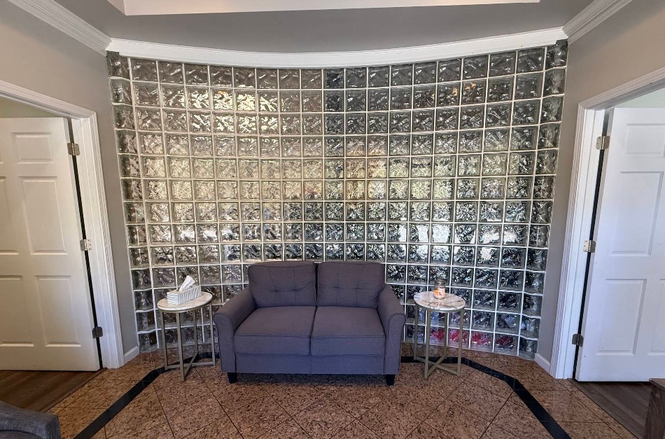 Waiting area with loveseat and glass block accent wall