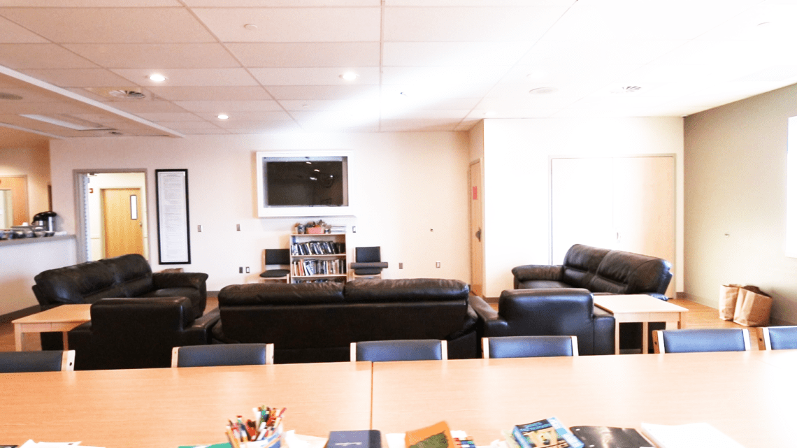 Lounge area with black leather sofas and a bookshelf
