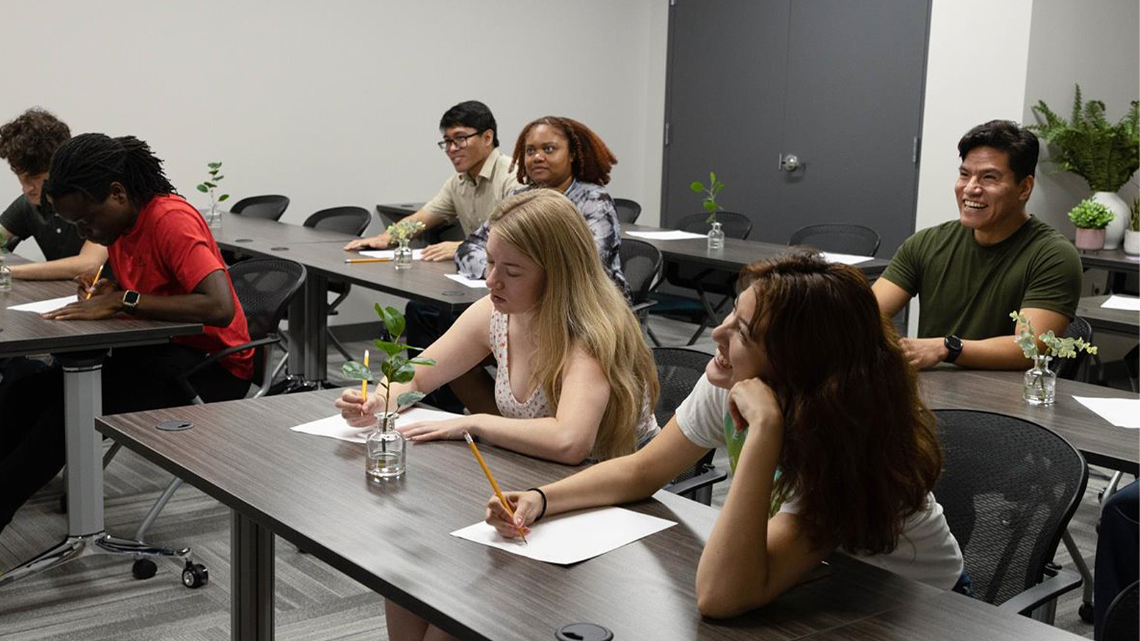 A group of people taking notes in a room with grey flooring.