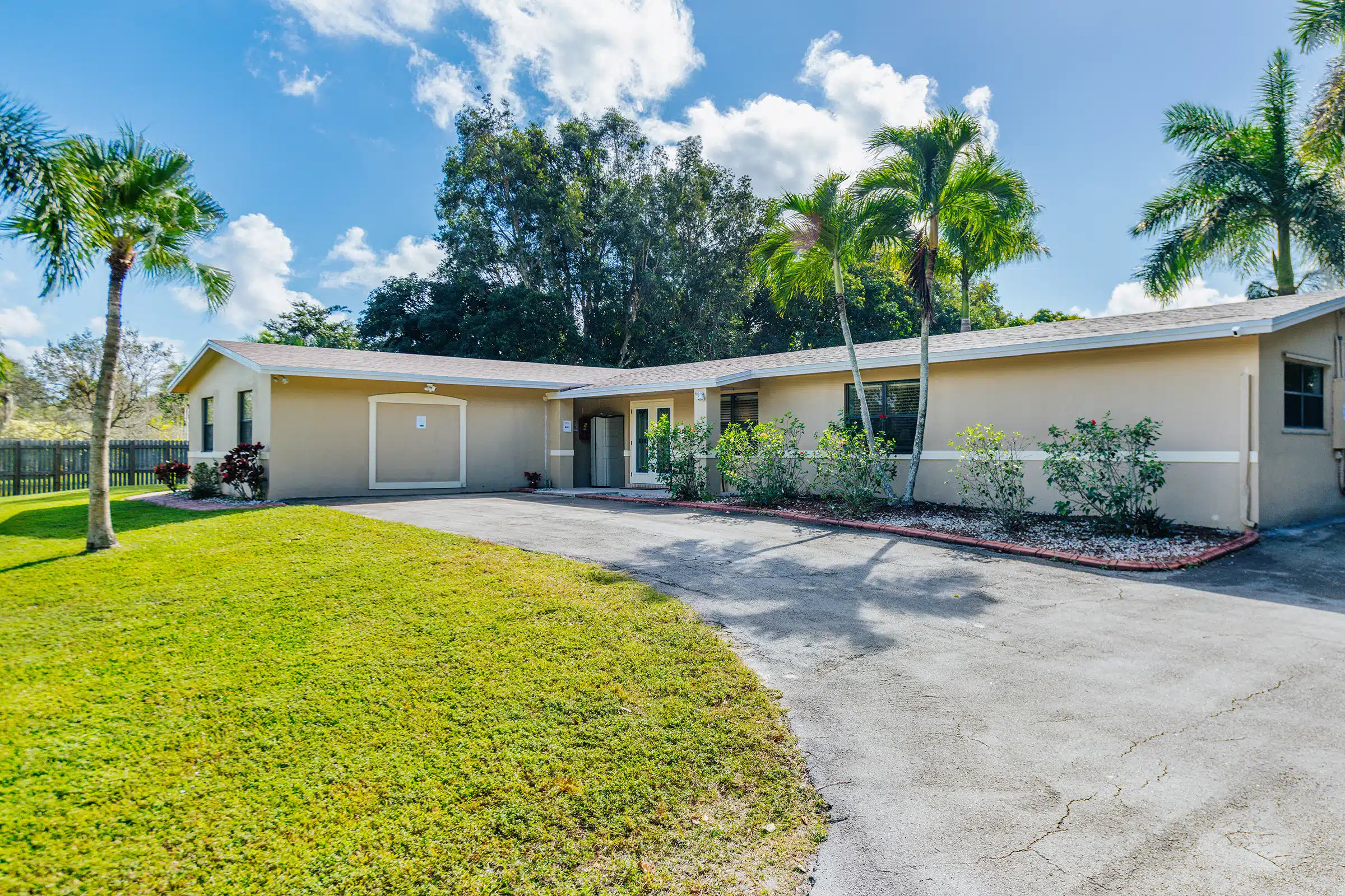 Single-story facility with driveway and palm trees