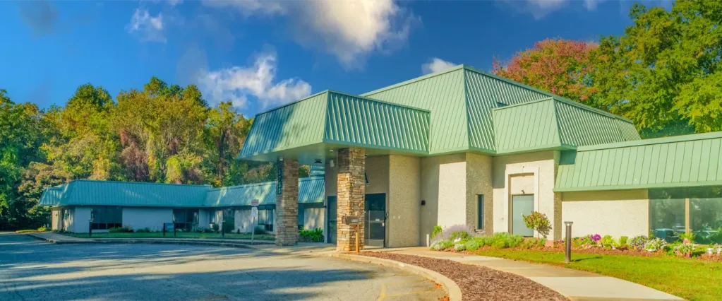 Rehab center exterior with green roof and wooded backdrop